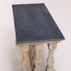 an old wooden table with black top and two legs on one side, against a white background