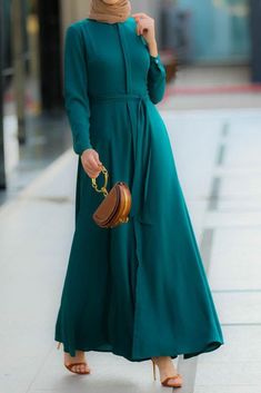 Introducing the Emerald Shirt Dress from Annah Hariri - a stunning and unique dress that is perfect for any occasion. Made from a lightweight polyester blend fabric, this dress is not lined for added comfort and breathability. The dress features buttons running all the way down the front, a detachable belt, and sleeves that are designed to be friendly for performing ablutions, making it perfect for women. It also has hidden buttons, making it breastfeeding-friendly. It can be easily cared for by Turkish Long Dresses, Pleats Dress, Be Friendly, Abaya Design, Turkish Dress, Modest Maxi Dress, Muslimah Outfit, Hijab Designs, Kaftan Abaya