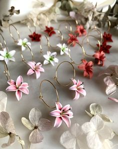 several different colored flowers are arranged on a white tablecloth with gold hoop earrings in the middle