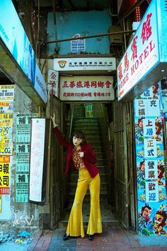 a woman standing in an alley way with her arms up