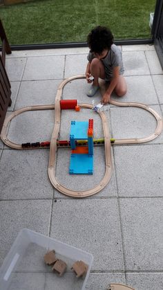 a child playing with a train set on the ground