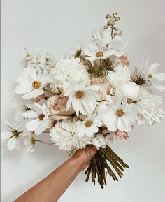 a hand holding a bouquet of white flowers