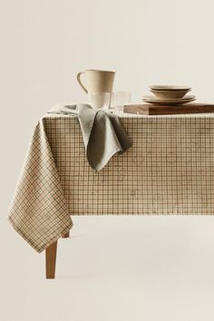 a table topped with plates and cups on top of a wooden table covered in plaid cloth