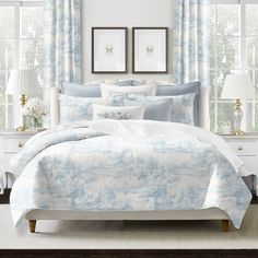 a white and blue bed in a bedroom next to two framed pictures on the wall