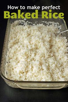 a glass dish filled with rice on top of a black table next to a metal spoon