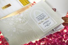 the wedding card is surrounded by rose petals and wine bottles on top of each other