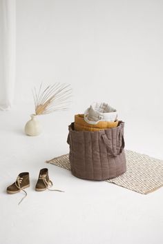 a pair of shoes sitting on top of a rug next to a basket and vase