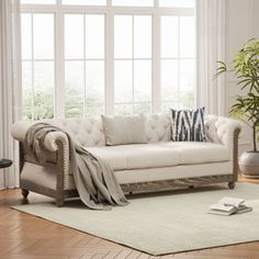 a living room with a white couch and pillows on the floor next to a large window