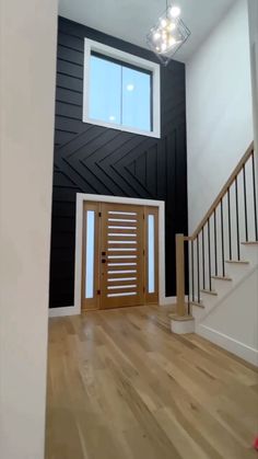 an empty room with a wooden door and stairs in front of a window on the wall