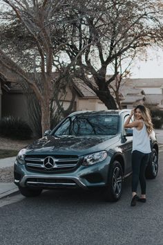 a woman standing next to a mercedes suv