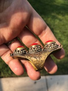 Beautiful vintage tribal saddle full finger ring Red gemstones or glass? Brass intricate carving Adjustable between sizes 9- 11. This is a gorgeous and very unique finger ring. There are three round cut cabochons and I am not sure what they are made of, they could be gemstone or they could be glass. The ring itself appears to be brass and someone could probably give it a good polishing if desired although I think it adds to the character the way it is. The ring Can fit anywhere from a size 9 thr Unique Metal Rings For Festivals, Unique Carved Ring Jewelry, Unique Toe Ring Jewelry For Festivals, Unique Ceremonial Toe Ring Jewelry, Unique Ceremonial Toe Ring, Unique Ceremonial Bronze Rings, Unique Festival Toe Rings, Unique Carved Bronze Jewelry, Unique Jewelry With Intricate Design