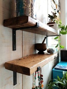 two wooden shelves on the side of a wall next to a potted plant and other items