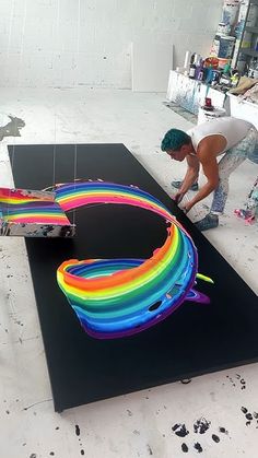 a man is working on an art project with neon colors and black paper in front of him