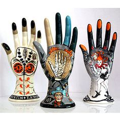 three ceramic hand sculptures with different designs on them