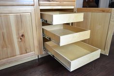 an open drawer in a kitchen with wooden cabinets and drawers on the bottom shelf,