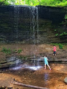 two children playing in the water near a waterfall