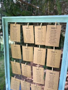 a table plan hanging on a blue frame with clothes pins attached to the pegs