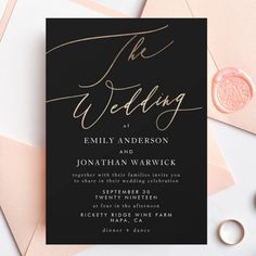 a black and gold wedding card with the word, the wedding on it next to some pink envelopes