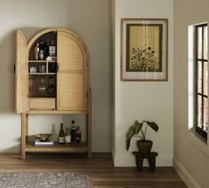 a wooden cabinet sitting in the corner of a living room next to a potted plant