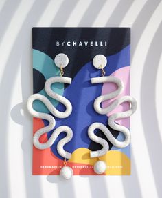 a pair of white earrings on top of a book with the title by chavelli