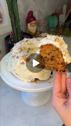 someone is cutting into a carrot cake on a white platter with a large knife