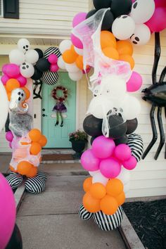 some balloons are hanging from the side of a house in front of a door that has a skeleton and ghost on it