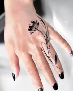 a woman's hand with a black and white flower tattoo on the middle finger