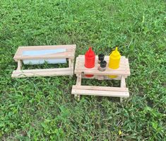 two wooden picnic tables sitting on top of a lush green field next to each other