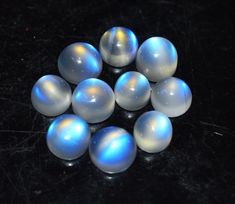 several white and blue marbles on a black surface with one light reflecting off the top