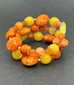 If your favorite color is yellow or orange and every color in between, this bracelet is perfect. There are beautiful oranges and yellow in this wrap bracelet and they are all stunning. The focal bead is a 16mm puffed orange circle slider. The beads around those are a swirled or marbled yellow and orange. There's also a mix of yellow and orange druzy beads. All of the metals are gold tone and include wavy spacers, pewter spikes, and two different kinds of bead caps. Fun Marble Fact: The longest marble run measures 9,379 feet. What is a druzy bead? Druzy are sets of tiny crystals of minerals formed on the surface of other stones. The overall appearance resembles that of sugar. The tiny crystals look like glitter when catching rays of light. Shipping Information All packages are shipped by Fi Orange Stackable Bracelets With Round Beads, Stackable Orange Round Beaded Bracelets, Spiritual Orange Beaded Bracelets As Gift, Orange Bohemian Bracelets With Spacer Beads, Orange Round Faceted Beads Jewelry, Orange Bohemian Bracelets With Colorful Beads, Orange Bohemian Beaded Bracelets With Faceted Beads, Bohemian Orange Bracelets With Colorful Beads, Unique Orange Bangle Jewelry