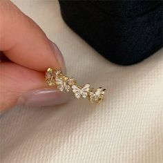 a close up of a person's hand holding a gold ring with flowers on it