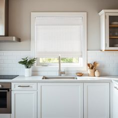 a kitchen with white cabinets and countertops has a window in the corner that is open