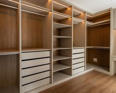 an empty walk in closet with lights on the ceiling and wooden shelves, along with white drawers