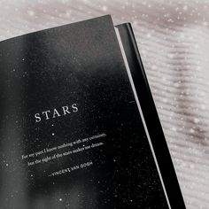 an open book with the words stars written on it and snow falling in the background