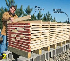 a man standing next to a pile of wooden pallets with instructions on how to build it