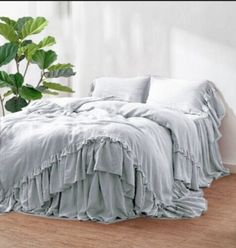 a bed sitting on top of a wooden floor next to a plant