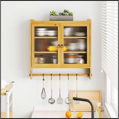 a wooden cabinet sitting above a sink in a kitchen next to a counter top with utensils on it