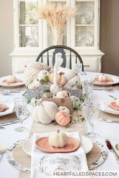 a table set for thanksgiving with pumpkins, gourds and other decorations on it