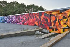 graffiti on the side of a building with steps leading up to it and trees in the background