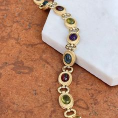 Estate/ vintage 14KT yellow gold Byzantine design, textured + cabochon, multi-gemstone link bracelet. Textured, shiny, and matte finishes on this piece. Slightly concave pieces with cabochon, amethyst, blue topaz, garnet, peridot, and citrine oval gemstones. Each gemstone measures: 7mm x 5mm; (8) total Rectangle byzantine + shiny open design links bracelet Measures 7.5", but fits shorter when clasped at the shorter length Weight: 22 grams Measures: 10mm wide Secure snap clasp Stamped 14K Great v Elegant Multicolor Cabochon Gemstones, Gold Oval Multi-stone Jewelry, Formal Multi-stone Oval Cabochon Jewelry, Elegant Multi-stone Oval Cabochon Jewelry, Luxury Gold Oval Cabochon Gemstones, Oval Gold Gemstones With Accents, Oval Cabochon Bracelet In Fine Jewelry Style, Gold Jewelry With Gemstone Accents In Oval Cabochon, Gold Jewelry With Gemstone Accents And Oval Cabochon