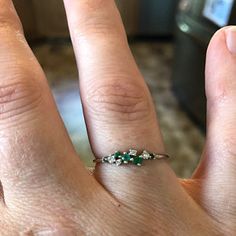 a woman's hand with an emerald and diamond ring on it