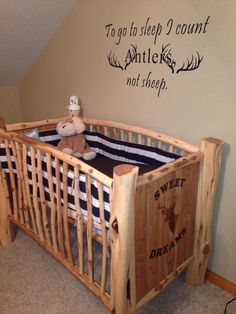 a wooden crib in the corner of a room next to a wall with writing on it