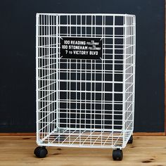 a white shopping cart sitting on top of a wooden floor next to a blackboard