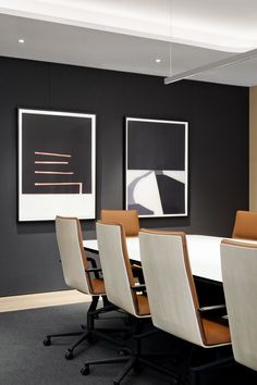 an empty conference room with chairs and art on the wall behind it in front of two framed pictures