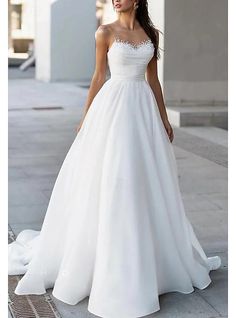 a woman in a white wedding dress standing on the sidewalk