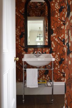 a bathroom sink sitting under a mirror next to a wall mounted faucet in front of a doorway