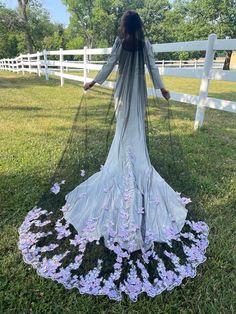 a woman standing in the grass with her back to the camera, wearing a dress made out of flowers