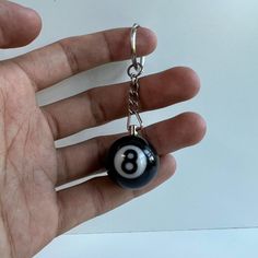 a hand holding a black and white ball keychain with the number eight on it