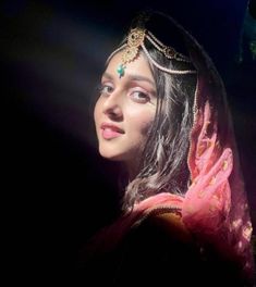 a woman wearing a veil and headpiece in the dark with lights on her face