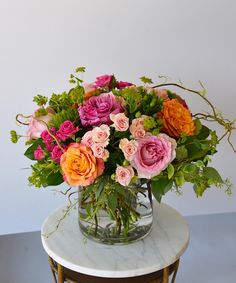 a vase filled with lots of different colored flowers on top of a marble topped table